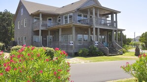 A two-story building with a balcony on the second floor, a covered porch, and a driveway. - Two If By Sea I and II: Larger home with fabulous views of Silver Lake (Ocracoke)