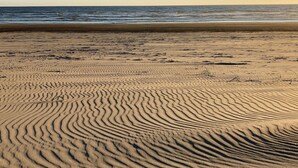 A sandy beach with visible ripples and a calm sea in the background. - Oregon Coast Lake front Oasis (Warrenton)