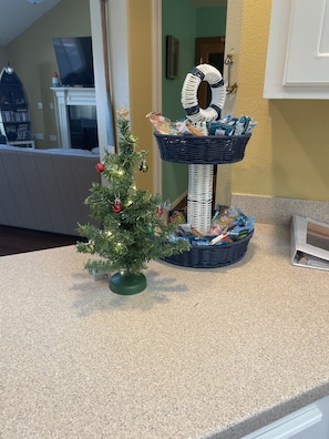 A kitchen counter with a small Christmas tree, a wicker basket, and a white cabinet.