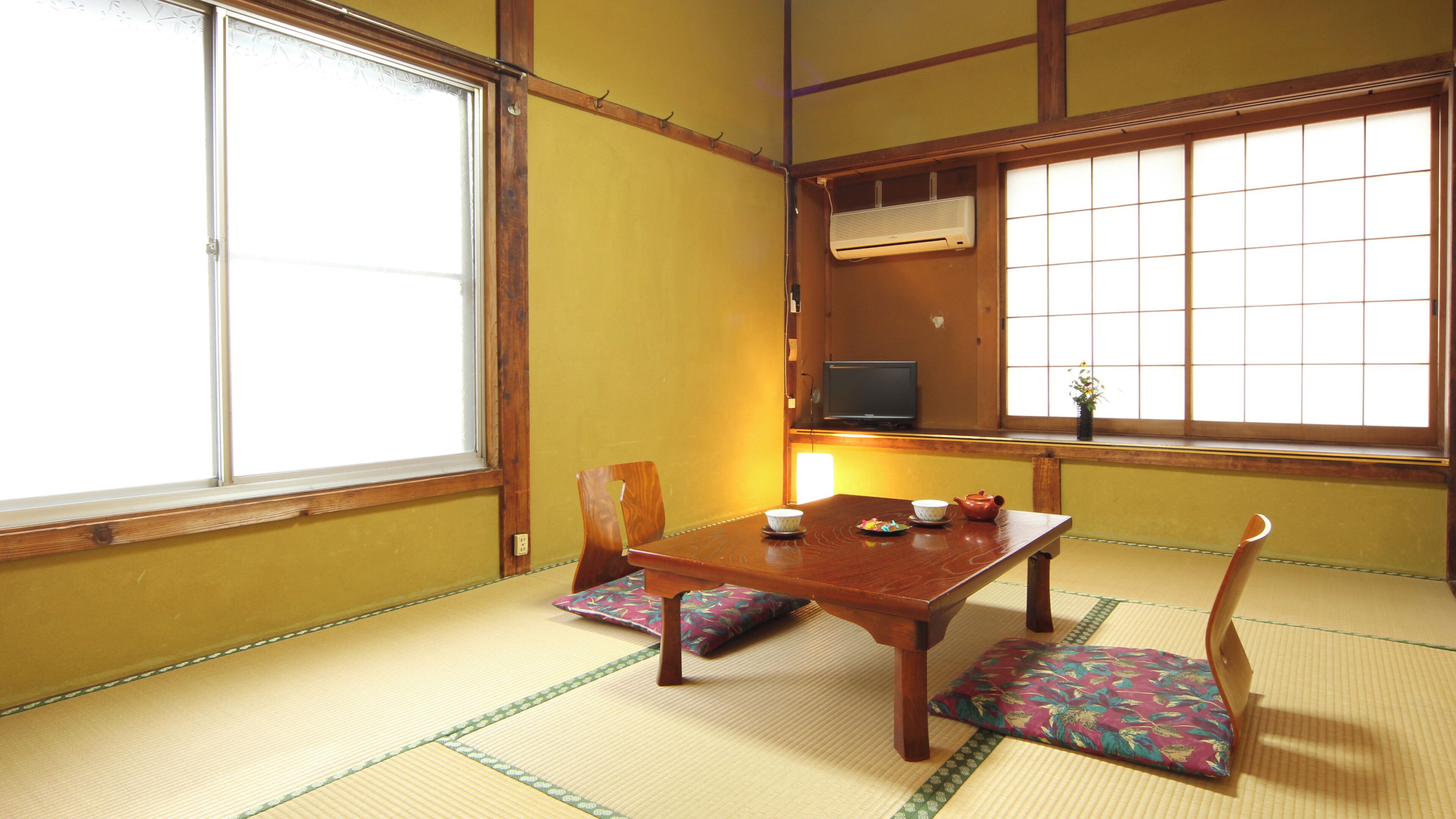 A traditional Japanese room with tatami flooring, a low table, and a television.