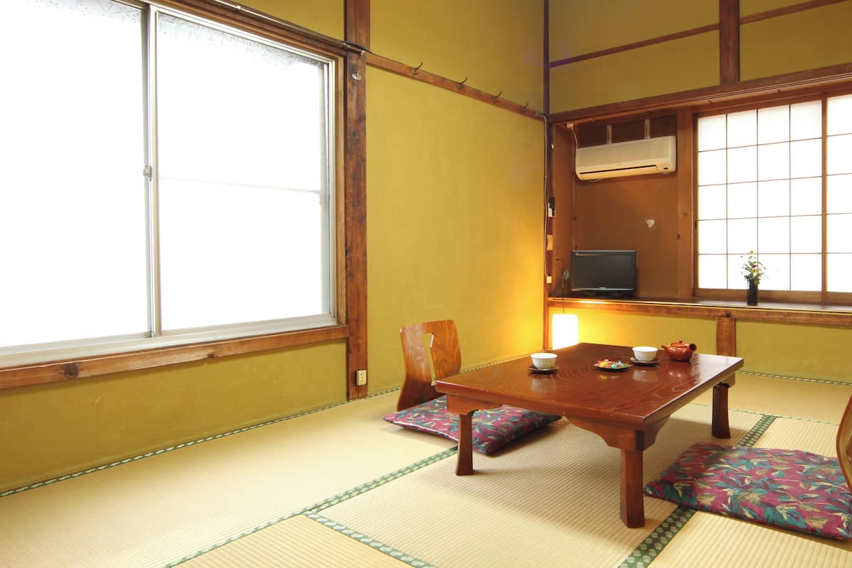 A traditional Japanese room with tatami flooring, a low table, and a television.