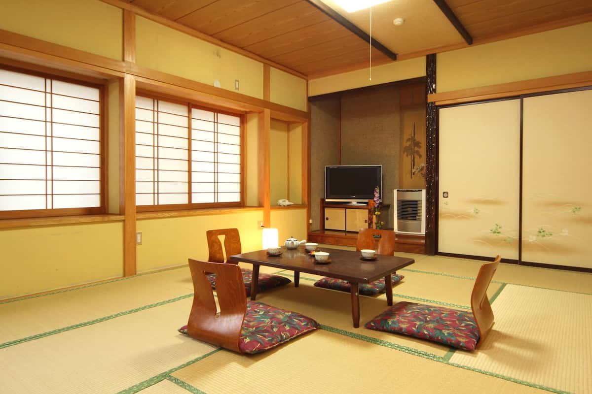A traditional Japanese room with tatami flooring, a low table with cushions, and sliding doors.