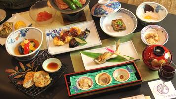 A variety of dishes and a glass of red wine on a table.