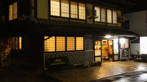 Un bâtiment japonais traditionnel, doté d’un sol recouvert de tatamis, d’une façade en bois et d’une enseigne accueillant les visiteurs.