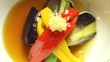 A bowl of soup with various vegetables and a piece of ginger.