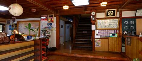 Un interior de madera con una escalera, estanterías de madera y un mostrador de recepción.