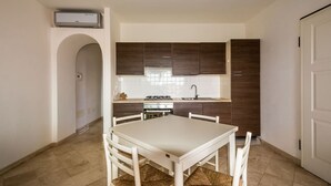 A compact kitchen with dark wooden cabinets, a white countertop, and a tiled floor. - Splendid Seaview Apartment (N° 20) (Porto Pozzo)