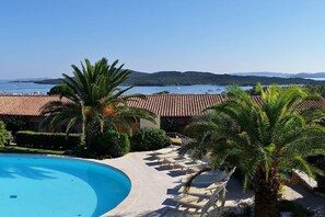 Un complexe hôtelier doté d’une piscine, de chaises longues et offrant une vue sur la mer.