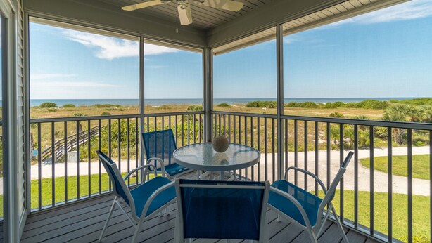A covered outdoor area with a table and chairs, overlooking a grassy landscape and the ocean. - Spend some time in this gorgeous villa with a gorgeous view! B3623A (Cape Haze)