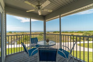 A covered outdoor area with a table and chairs, overlooking a grassy landscape and the ocean. - Spend some time in this gorgeous villa with a gorgeous view! B3623A (Cape Haze)