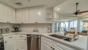 A modern kitchen with white cabinets, stainless steel appliances, and a dishwasher. - Spend some time in this gorgeous villa with a gorgeous view! B3623A (Cape Haze)