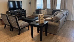 Ein Wohnzimmer mit einer Couch, zwei Sesseln, einem Couchtisch, einem Fernseher und einem Schrank.