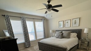 Ein Schlafzimmer mit einem großen Bett, einem Deckenventilator, einem Schminktisch und einem Sessel.