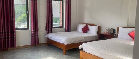 A hotel room with two beds, a wooden headboard, a nightstand, and a window with curtains.