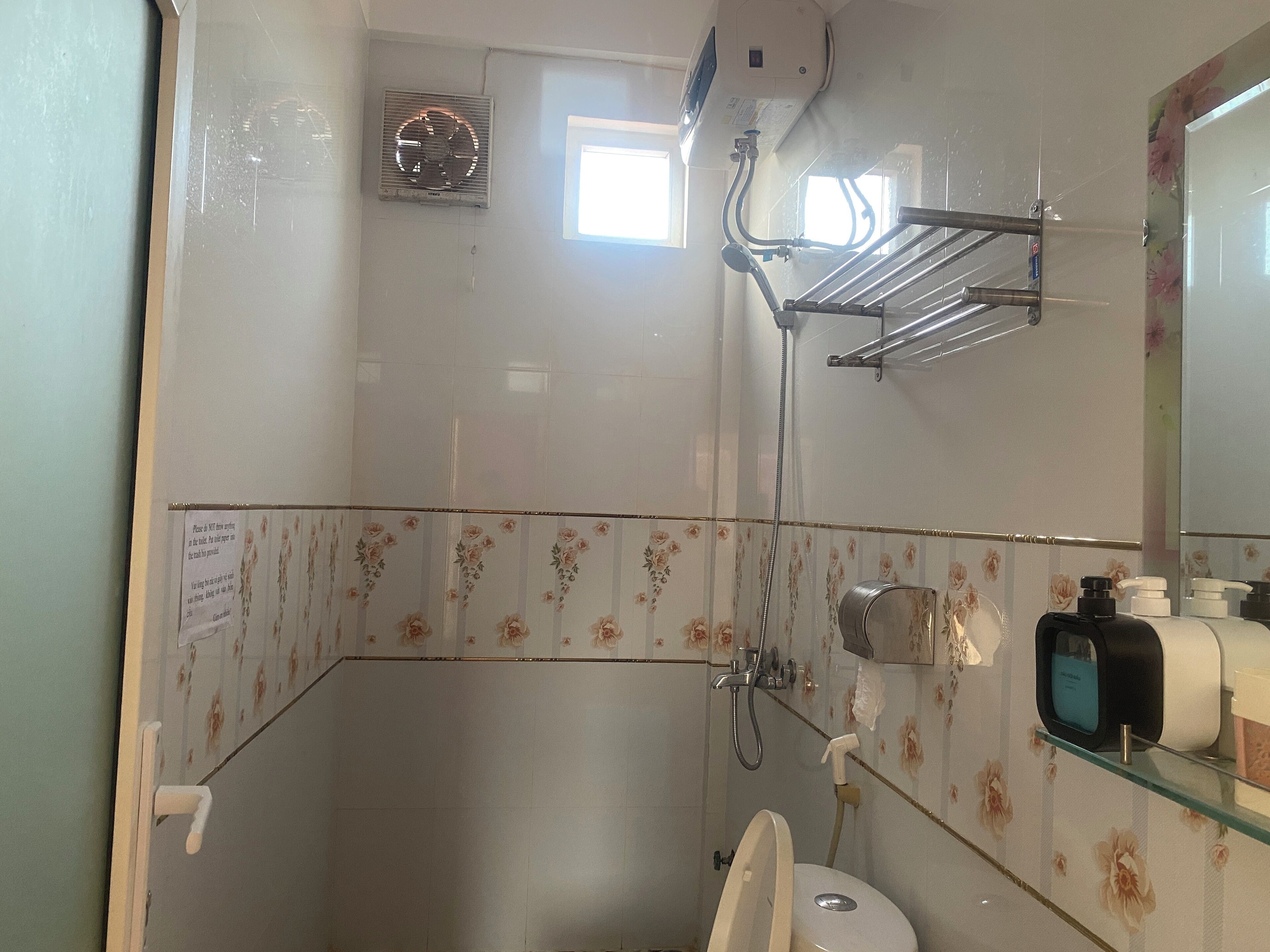 A bathroom with a shower, toilet, and a glass shelf with toiletries.