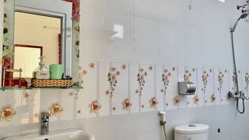 Casa de banho com lavatório, espelho e chuveiro.