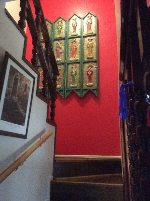 Een trap met een rode muur en een houten leuning.