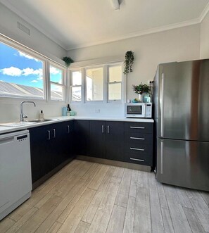 Una cucina moderna con un frigorifero in acciaio inossidabile, mobili scuri, un forno a microonde e una finestra vista sul tetto.