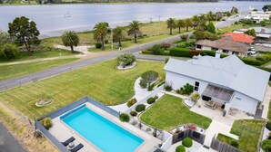 A residential property with a swimming pool, a well-maintained lawn, and a view of a lake.