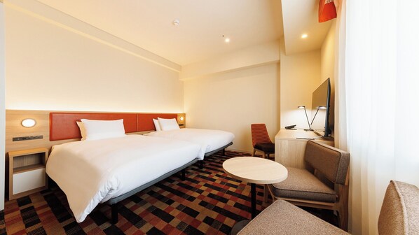 Habitación de hotel con una cama grande, un escritorio con silla, una mesita redonda y un televisor.
