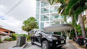 Un camionnette noire était garée devant un bâtiment moderne sur lequel on pouvait lire l’inscription « COZY RESORT ».