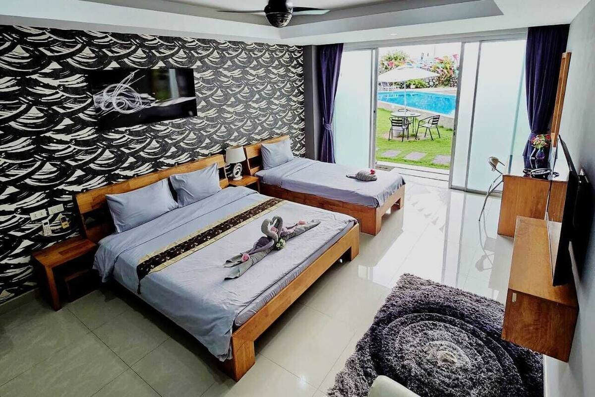Une chambre moderne avec deux lits, un ventilateur de plafond, une télévision et une vue sur une piscine.