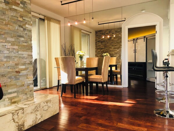 A modern dining area with a stone accent wall, a round table, and cushioned chairs.