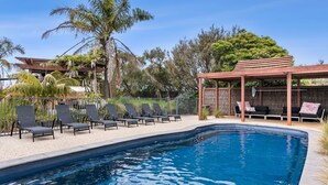 Una piscina con lettini e una zona relax coperta.