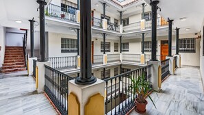 Ein mehrstöckiger Atrium mit Marmorböden, schwarzen Geländern und einer zentralen Treppe.