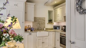Una cocina con armarios blancos, salpicadero de mármol, microondas, horno y un lavabo.