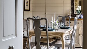 Un comedor con una mesa de madera dispuesta para cuatro personas, rodeada de sillas tapizadas.