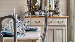 A dining table set with glassware, plates, and cutlery, a vase with flowers, and a mirror above the table. - Rectory Cottage -  a beautiful cottage sleeping two guests (near Stamford)