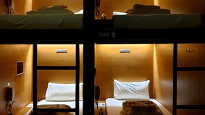 Habitación con literas dobles, cada una con almohada y manta. Hay un teléfono en la pared y una botella en el suelo.