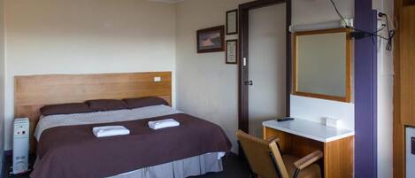 Une chambre d’hôtel avec un lit, un bureau, une chaise, une télévision et une porte.