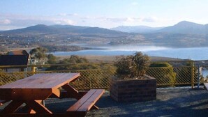 A picnic area with tables and benches overlooking a lake and mountains. - Snowy Valley - Hostel (East Jindabyne)
