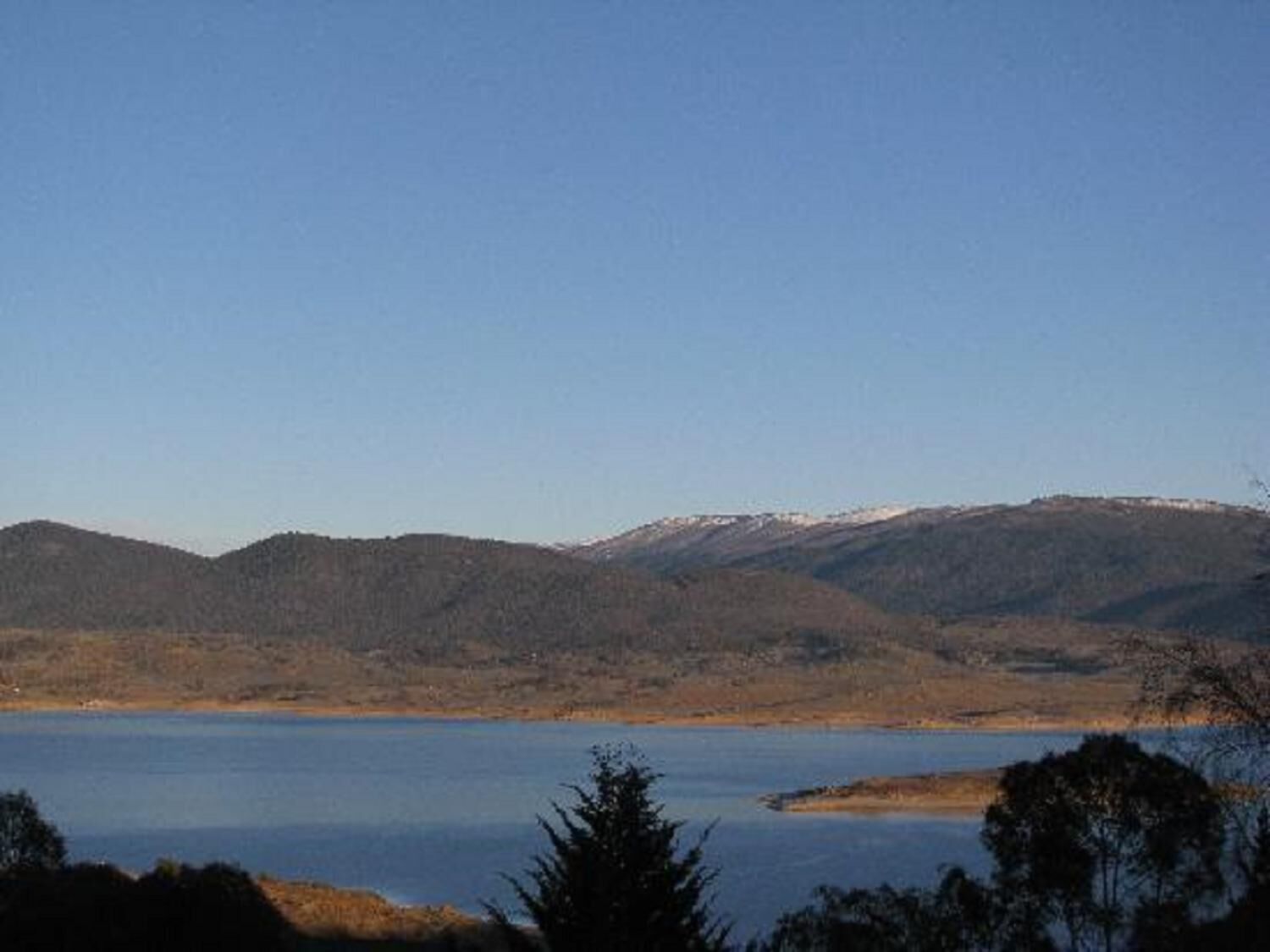 A lake surrounded by mountains with a clear sky.