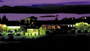 A building with multiple windows and a parking lot with cars. - Snowy Valley - Hostel (East Jindabyne)