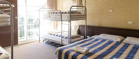 A hotel room with bunk beds, a large window, and a brick wall.