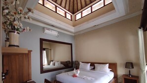 A bedroom with a large bed, a wooden desk, a mirror, and a ceiling fan. - Villa Sahabat (Gili Trawangan)