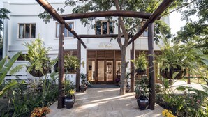 A courtyard with a wooden pergola, potted plants, and a building entrance labeled "Villa Bagan".