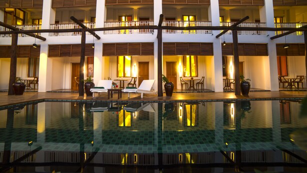 A hotel with a pool, multiple balconies, and outdoor seating areas.