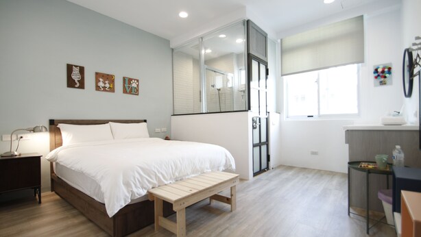 Une chambre à coucher comprenant un lit, une table de chevet, un banc et un grand miroir.