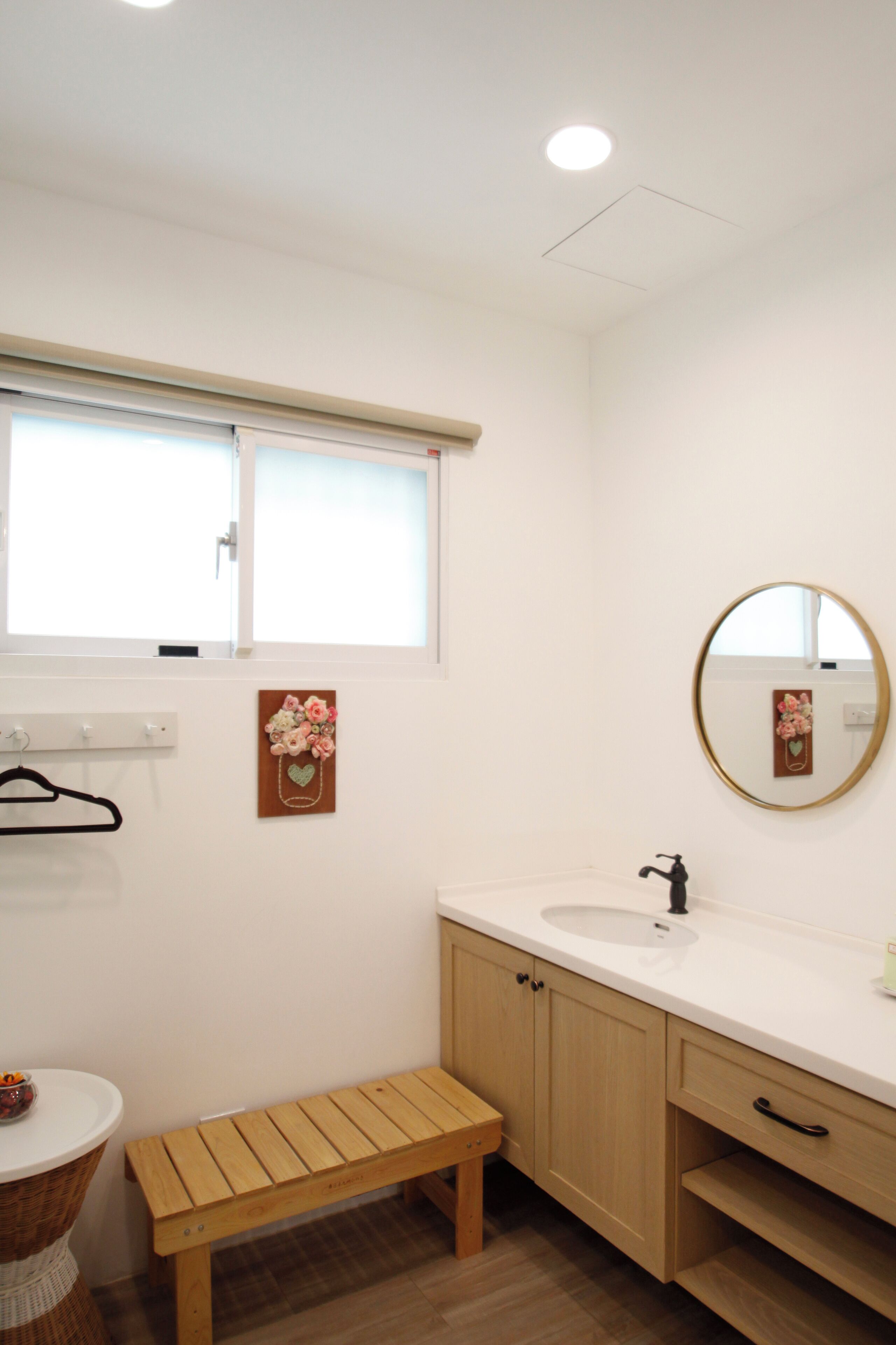 A bathroom with a wooden bench, a sink, and a mirror.