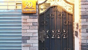 A brick building with a metal gate, a number sign '20 Macchiato', and a light fixture above the gate. - Macchiato (Tainan)