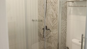A modern bathroom with a glass shower enclosure, a toilet, and a marble-patterned wall. - Macchiato (Tainan)