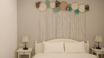 A bed with white bedding, two bedside tables with lamps, and a wall hanging with circular designs.