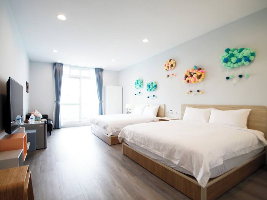 Une chambre d’hôtel avec deux lits, un bureau, une télévision et une fenêtre avec des rideaux.