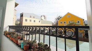Un balcon orné de plantes en pot, avec vue sur les immeubles.