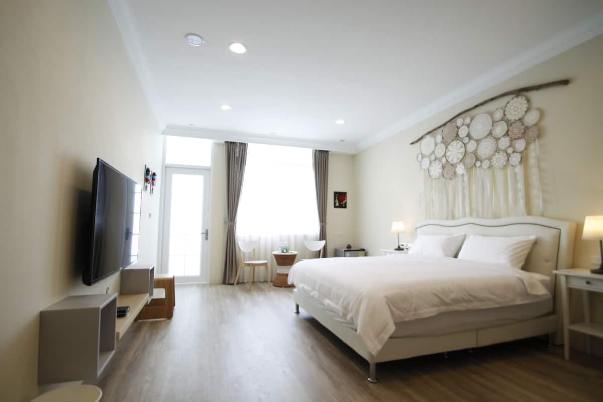 Ein modernes Hotelzimmer mit einem großen Bett, einem Flachbildfernseher, einem kleinen Tisch und einer dekorativen Wandgestalt.