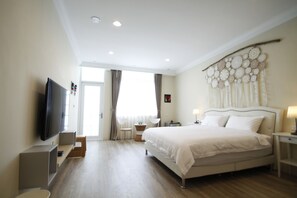 A modern hotel room with a large bed, a flat-screen TV, a small table, and a decorative wall hanging. - Macchiato (Tainan)
